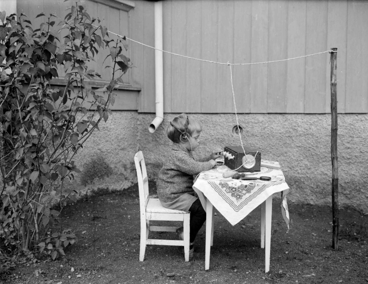 Liten gutt sittende ved et bord. Radioamatør. Gunnar Berge på "radio".