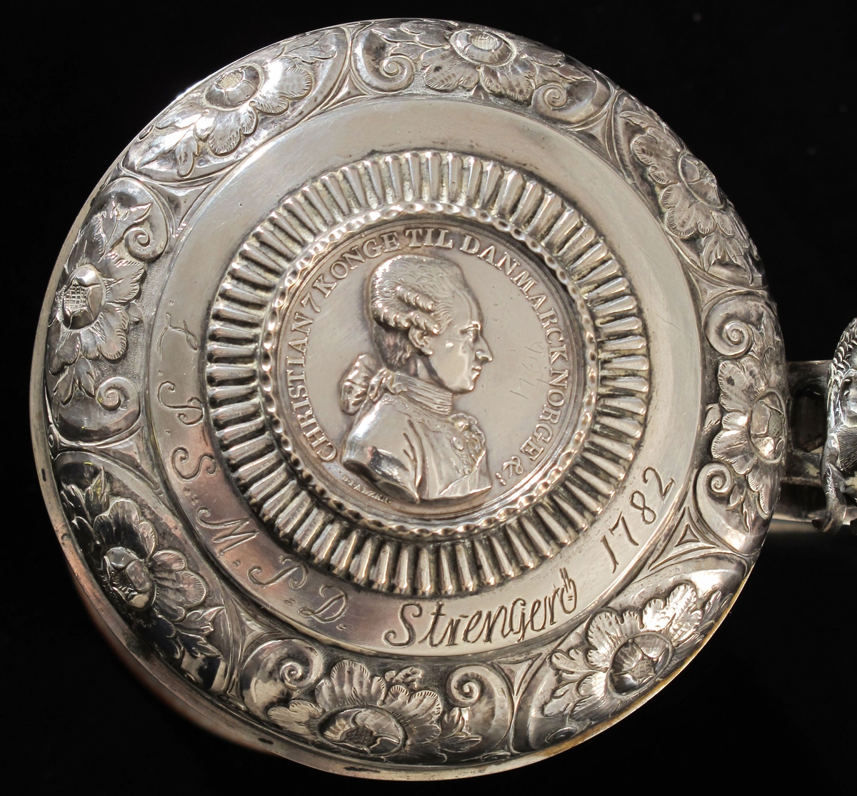 Polykrom blomsterdekor på kruset,  kongens portrett på medaljen. Havhest .