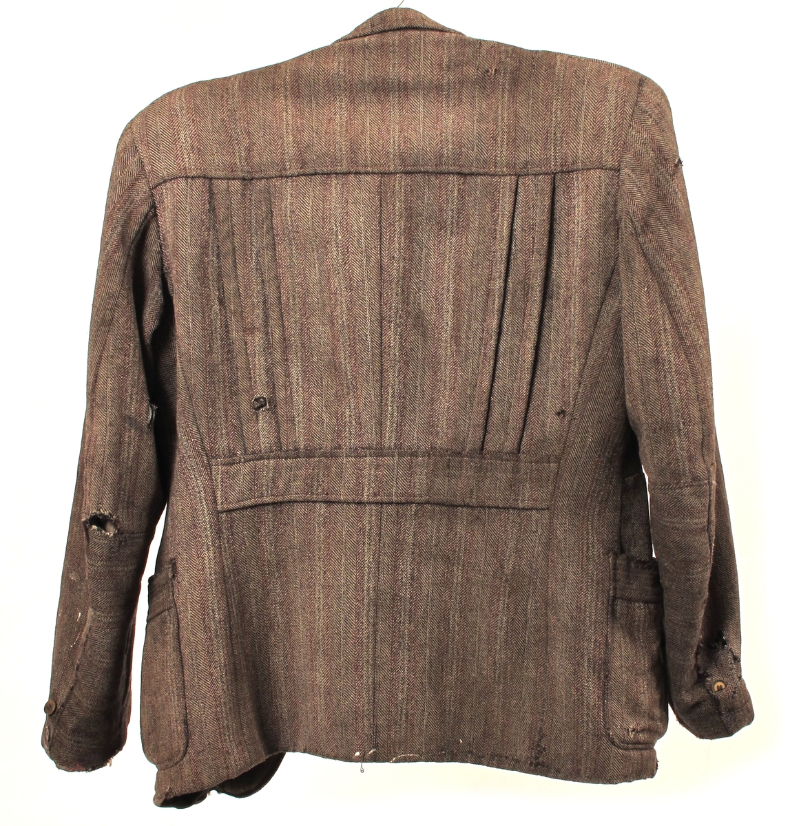 Stipet stoff, krisevare produsert under 2.verdenskrig, blanding av ull og cellull, som ble laget av cellulose. Foret var gammelt - enten noe de hadde liggende, eller sprettet av gamle klær.  Snittet er litt spesielt, trolig for å utnytte små biter stoff.