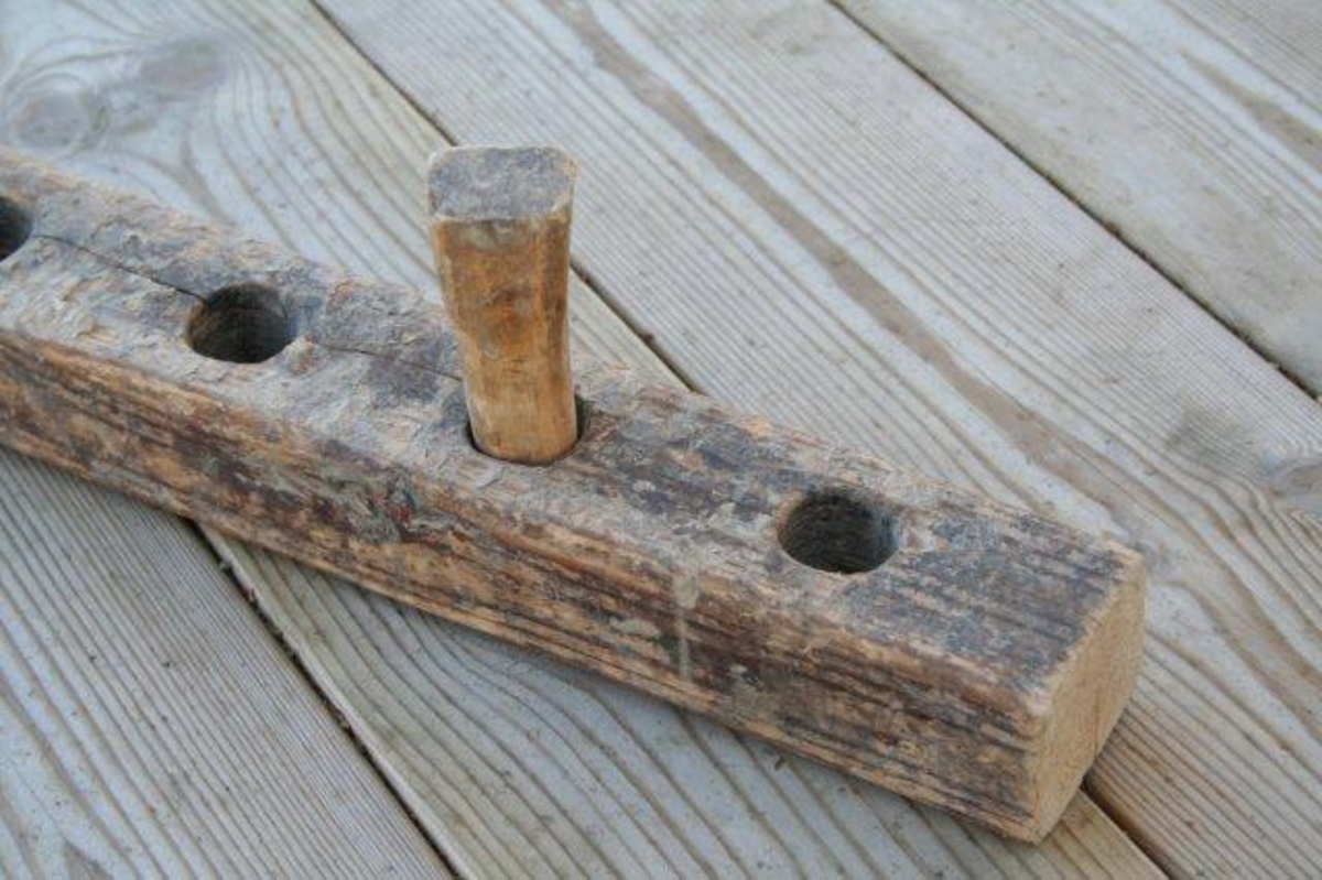 Lang arm med syv hull. Fast endeknekt med spindel (skrue) innfelt i armen. Motknekt i form av tapp  som kan flyttes fra hull til hull.