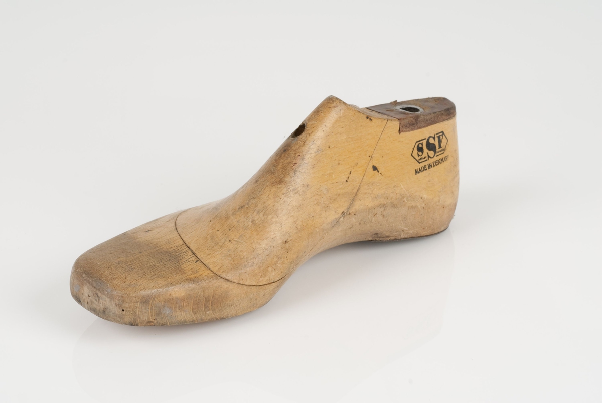 En tremodell i to deler; lest og opplest/overlest (kile).
Høyrefot i skostørrelse 38, og 8 cm i vidde.
Hælstykket i metall.