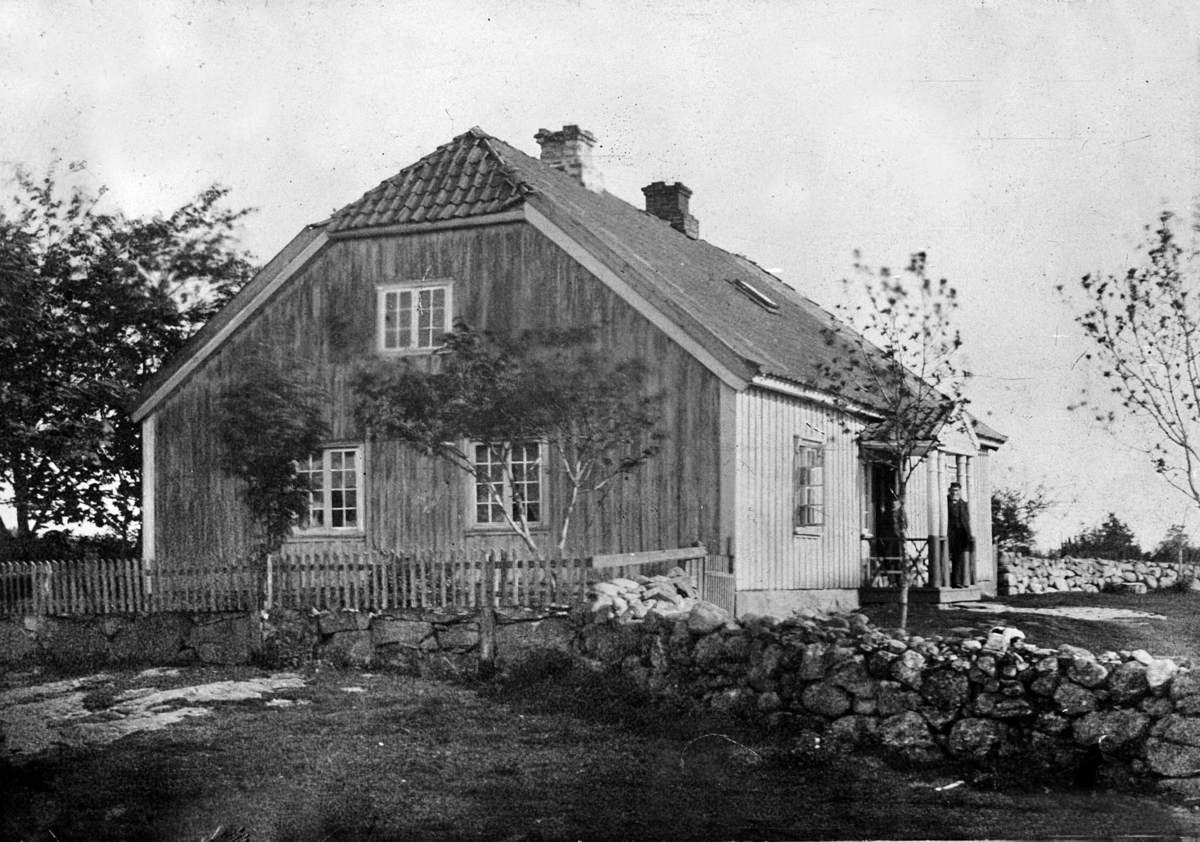 Hovedbygningen på Otterstad med steingjerder og stakittgjerde rundt hagen. Huset har fått tak over inngangen båret av søyler.