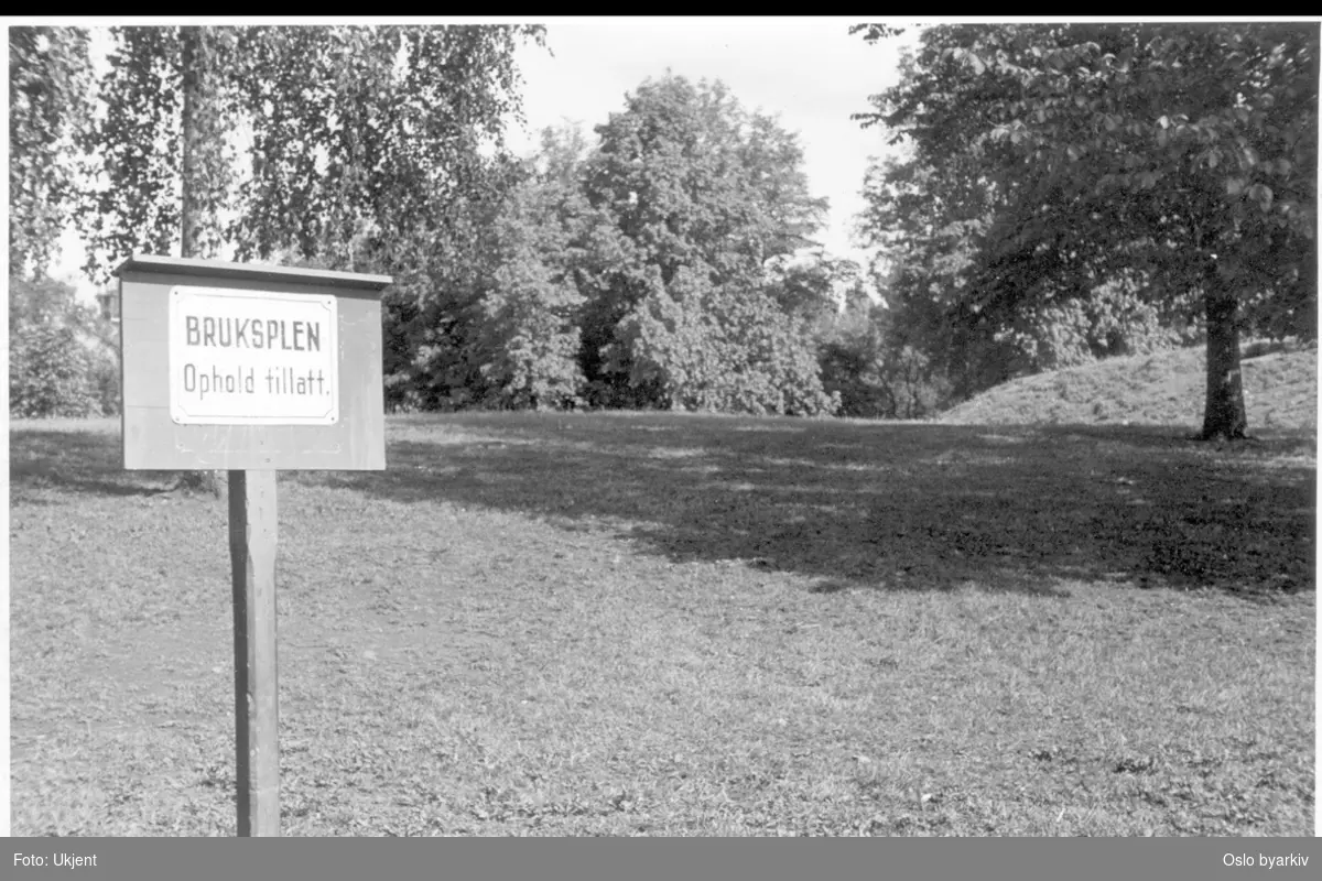 Plen og parktrær i parken. Skilt med teksten : "BRUKSPLEN Ophold tillatt".