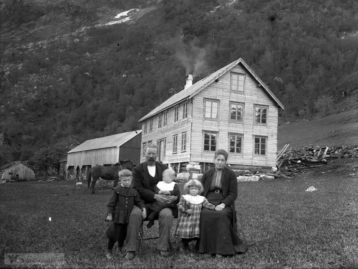 Frå Hoem ved Eikesdalsvatnet. .Familien flytta til Oppigard gbr.79-12 i 1919. Stuebygningen var ny i 1914..Husa er fra venstre: Stua opp for kaia der Edvard Hånde med familie bodde (se nr 074), stua "hennar Anne Hoem" (bak løa), fjøset/løa og det nye våningshuset som de flyttet inn i 1914. .Datra Kristine f.1914 er 14 dager gammel og ligger inne når bildet ble tatt.