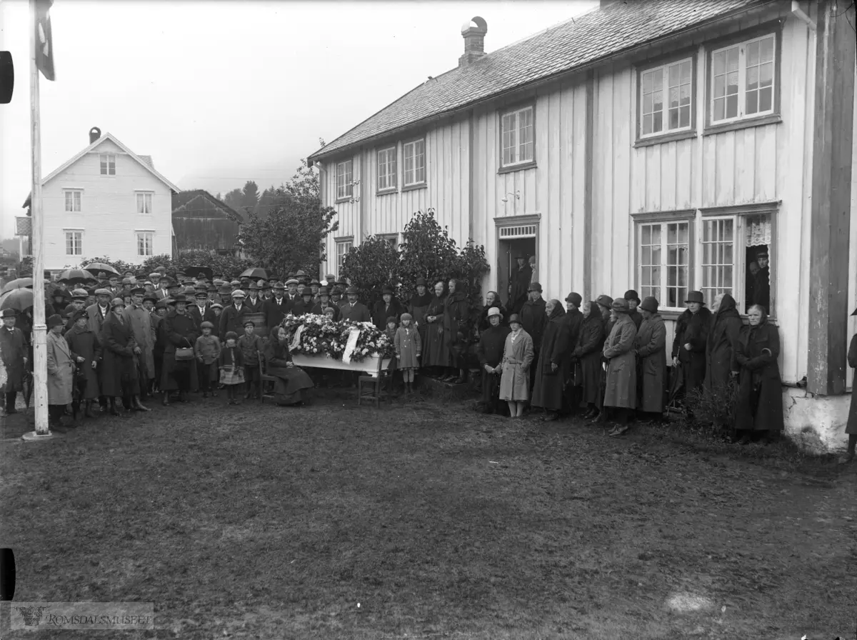 Mest sannsynlig Ole Emil f.1896 d.1928 sin gravferd..Noe usikkert hvilken begravelse men, Ingeborg Ivarsdatter Skjellbostad f.26.08.1853 d.1933 g.m Ole Ivarson..Ole Emil f.1896 d.1928..Det kan være en av disse begravelsene..Det sitter en gammel kone på en stol foran kista. Kan det være mora Ingeborg slik at dette er sønnen Ole Emil sin begravelse i 1928..Skeide Framigard i bakgrunnen.