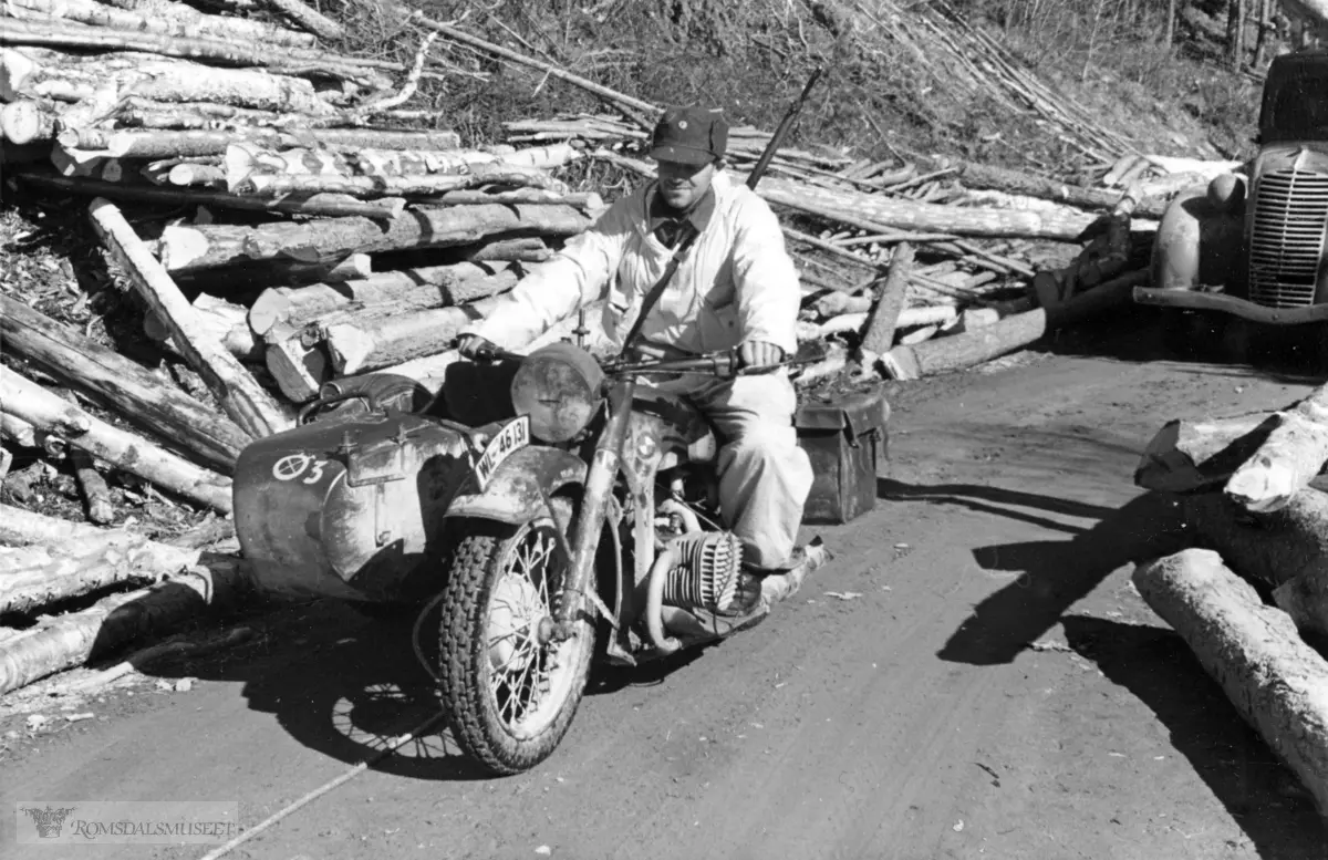 Norsk soldat på den ene tyske motorsykkel som var intakt etter trefningen ved Einunna. BMW R12 fra Regiment Herman Göring, Kradschützen kompani. .Motorsykkelen på bildet er en BMW R12. Vi ser tydelig at sykkelen er merket med "motorsykkelavdelingsmerke" og at sykkelen er nr 3 i avdelingsrekken.."Krigsbytte"."Tyskerne fulgte ikke efter over Solliam men kom opp fra Tynset over Alvdal. De hadde nok ventet at våre avdelinger var pulverisert av bombeflyene og satte derfor inn mindre styrker som ble slått tilbake og efterlot blodpøler og vogner i veiene".Legg også merke til den hvite kalken som man ser rester av på sykkel og sidevogn. Tyskerne brukte denne formen for kamuflasje under angrepet på Norge i 1940.