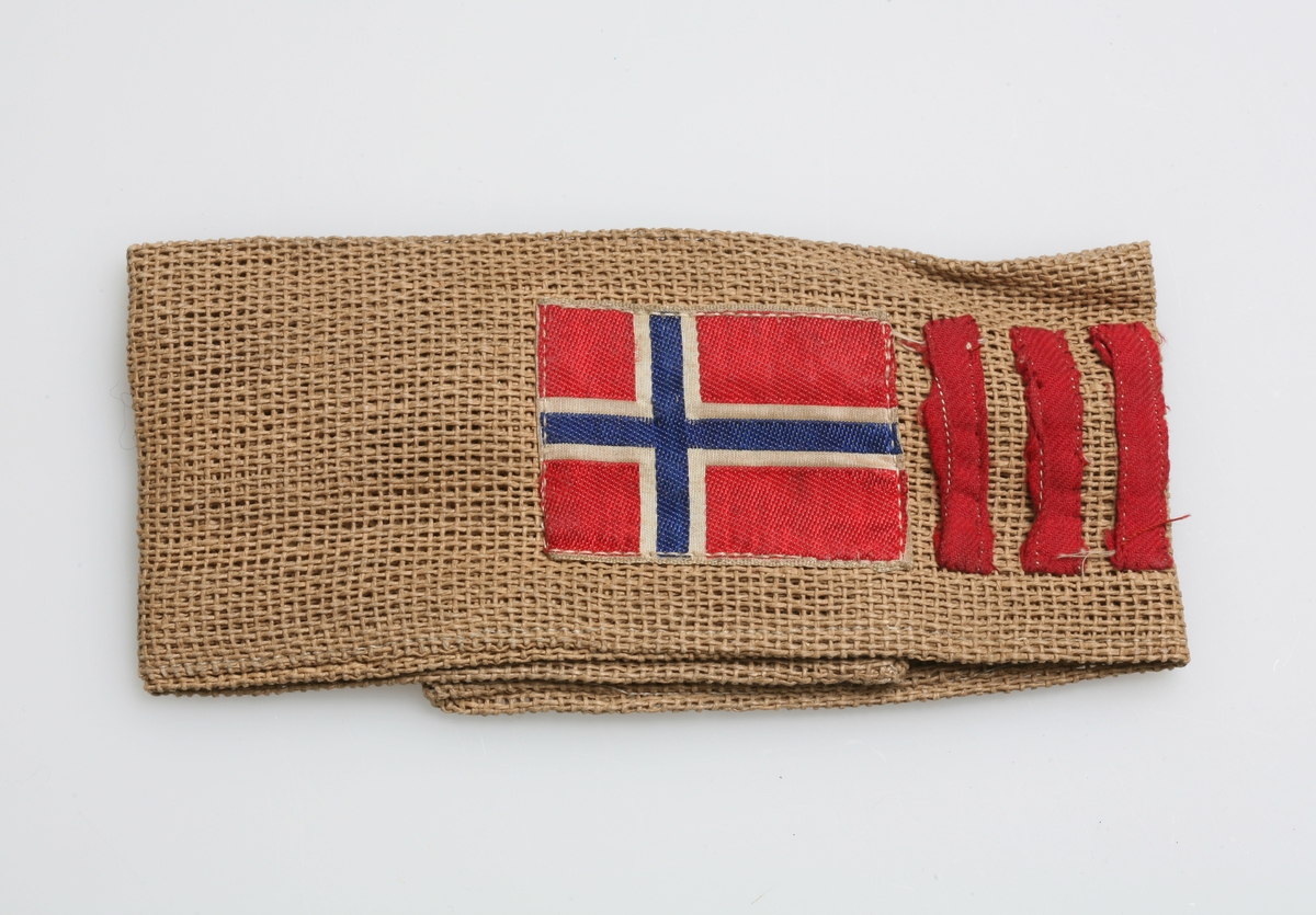 Norsk flagg og fire røde render er sydd på