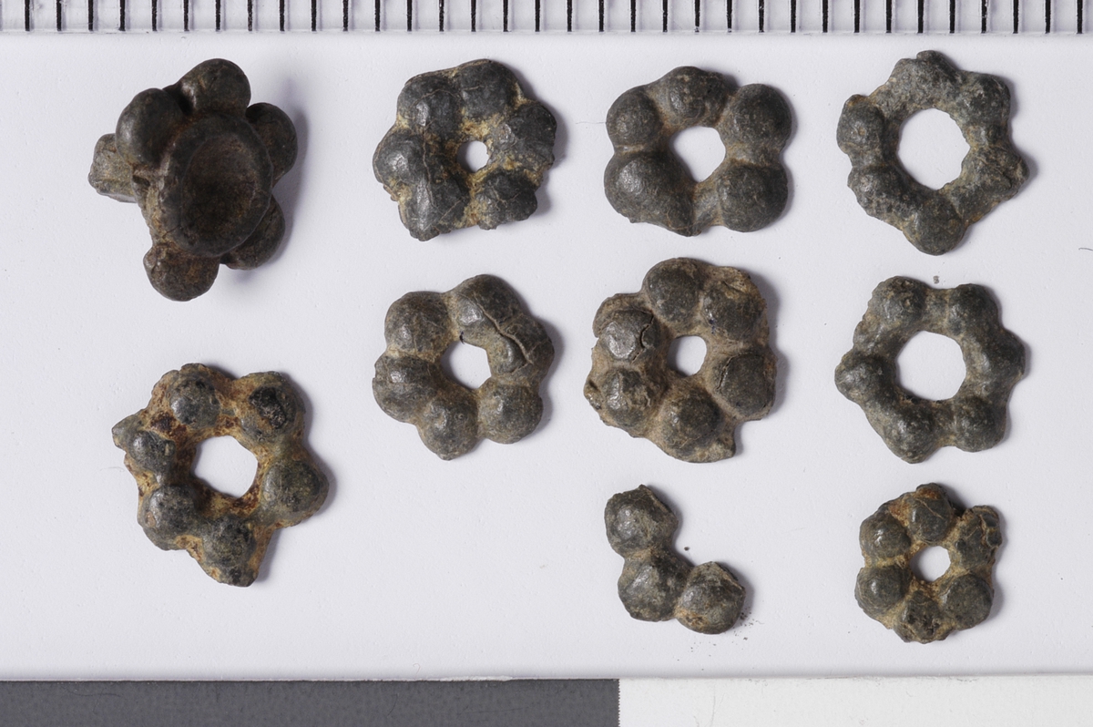 MALV: DIAM. 6 MM, 6-BLADET ROSETTFORMET MED HULL I MIDTEN. 1 HAR NAGLENSITTENDE I. 1 ER FRAGMENTARISK. REF. FINGERLIN FIG. 148-158. POST-MEDIEVAL ARCH. 15 (1981) FIG. 79-83. 