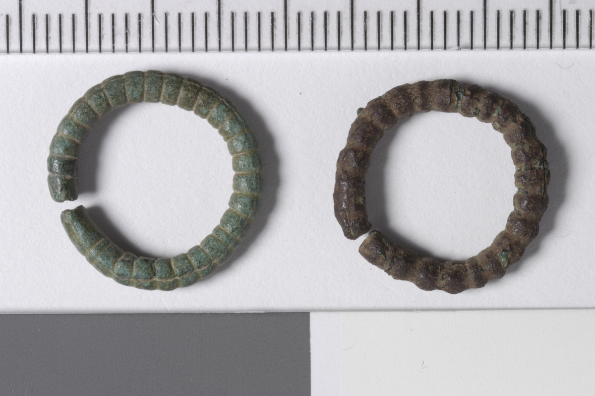 MALV: DIAM. 16  T. 2, 4 MM, STØPT ÅPEN RING MED TVERR-RIFLER SOM DEKOR. SE FIG. XLV NR. 4 (BONDESYLV). TORNEN MANGLER. ANALOG, MEN NOE STØRRESE HK 4705. DISSE KAN OG HA VÆRT UTSTYR TIL ET RINGBELTE (SE FIG. 171 -
