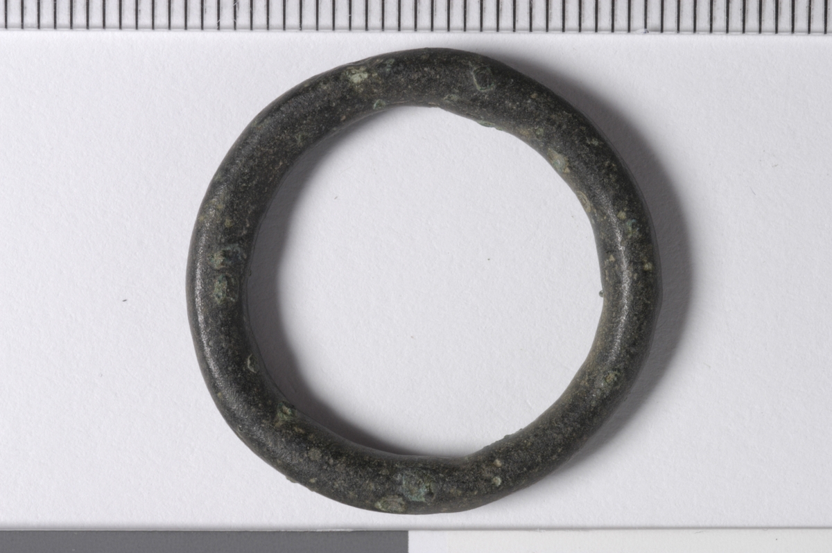 MALV: DIAM. 28, 1  T. 4 MM, RINGFORMET LAGET AV ET BÅND MED 4 MM TYKT RUNDTTVERRSNITT. TORNEN MANGLER. SE PLATE LXXVII NR. 1 OG 2, (MEDIEVAL CATALOGUE - LONDON MUSEUM 1967). 