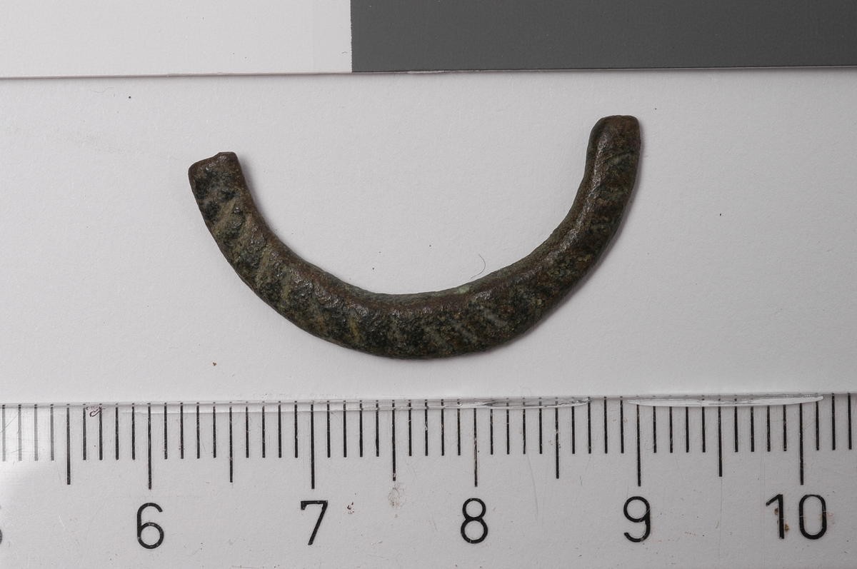 MALV: DIAM. 27, 5  T. 4, 1 MM, FRAGMENTET ER LAGET AV FLATT 4, 1 MM BREDT BÅND. DENENE SIDEN HAR RIFLE-DEKOR. TORNEN MANGLER. 