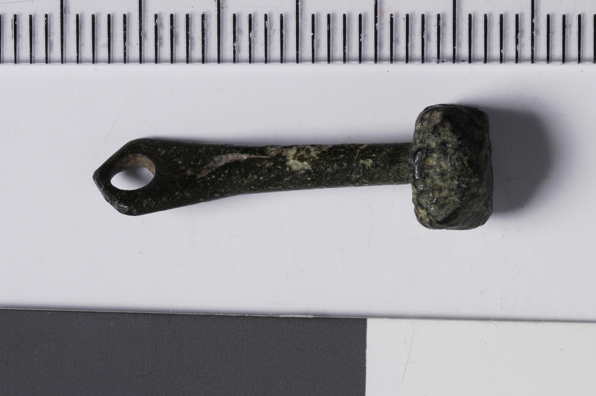 MALV: SE BESK., L. 25 MM, SKAFTETS B. 6 MM, AVST. 6, 8 MM. RUNDT SKAFT HVOR ENE ENDEN ER FLATET UT OG HAR ET HULL, MENS ANDREENDEN ER FORMET SOM ET MANGEKANTET HODE. 