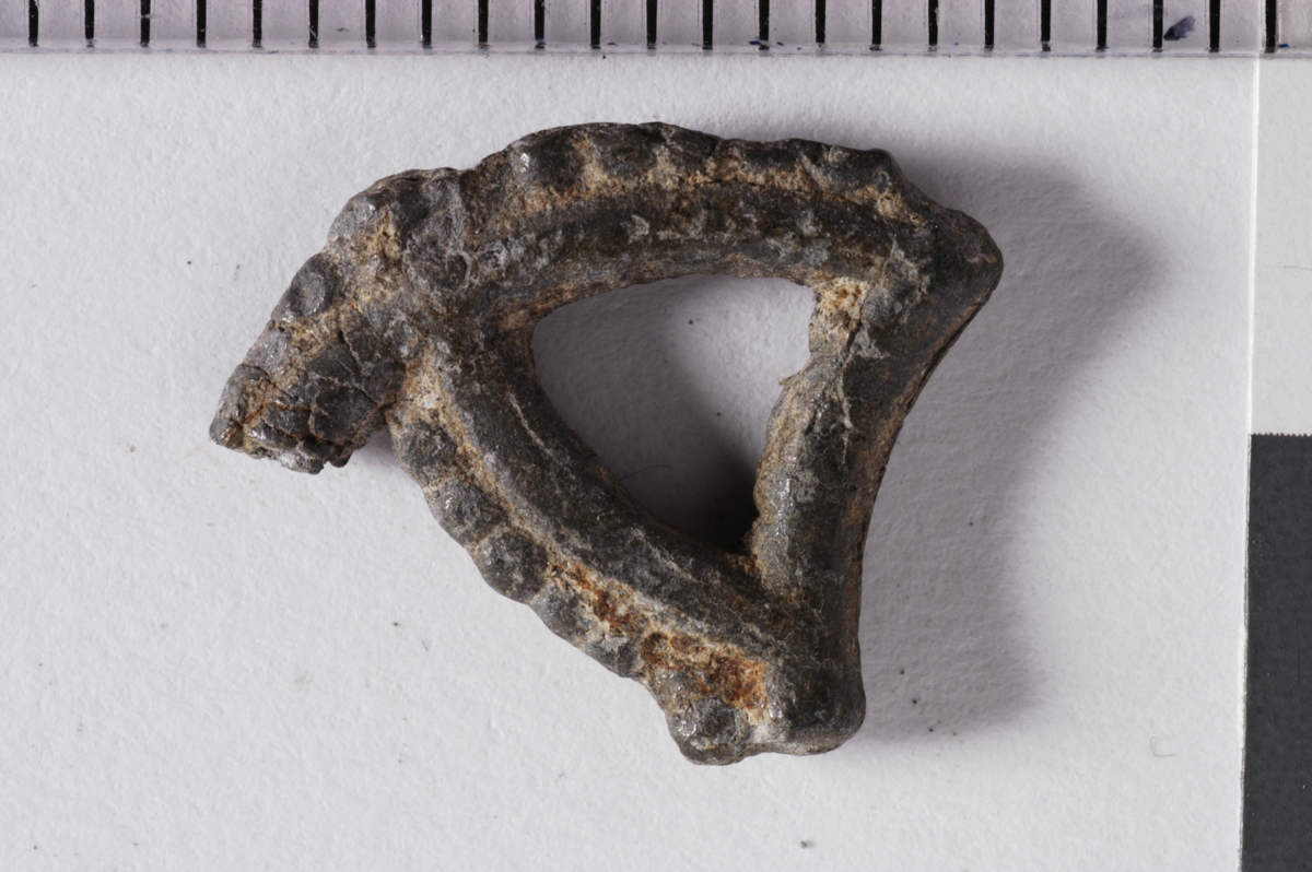 MALV: ST. M. 15  B. PÅ BÅNDET 2, 2 MM, FRAGMENT AV EN UTSTANSET DEKOR. 