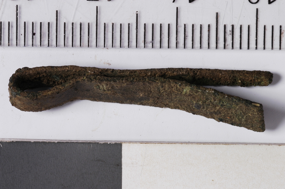 MÅL: L. 3, 2 CM, ST. B. 0, 6 CM, CA. 1 MM TYKK, AVSMALNENDE PLATE SOM ENDER I EN SPISS. OMBØYD.
