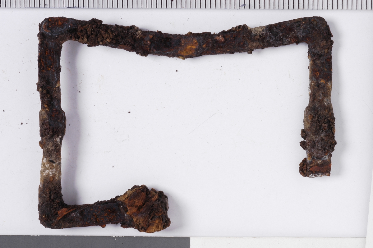 MÅL: B. 6, 0 CM H. 4, 4 CM, MULIG BRUKT TIL SKRIN. BRUKKET AV I ENE ENDEN. NOE UJEVNT, FLATT JERN, FORMET SOM ET REKTANGEL.