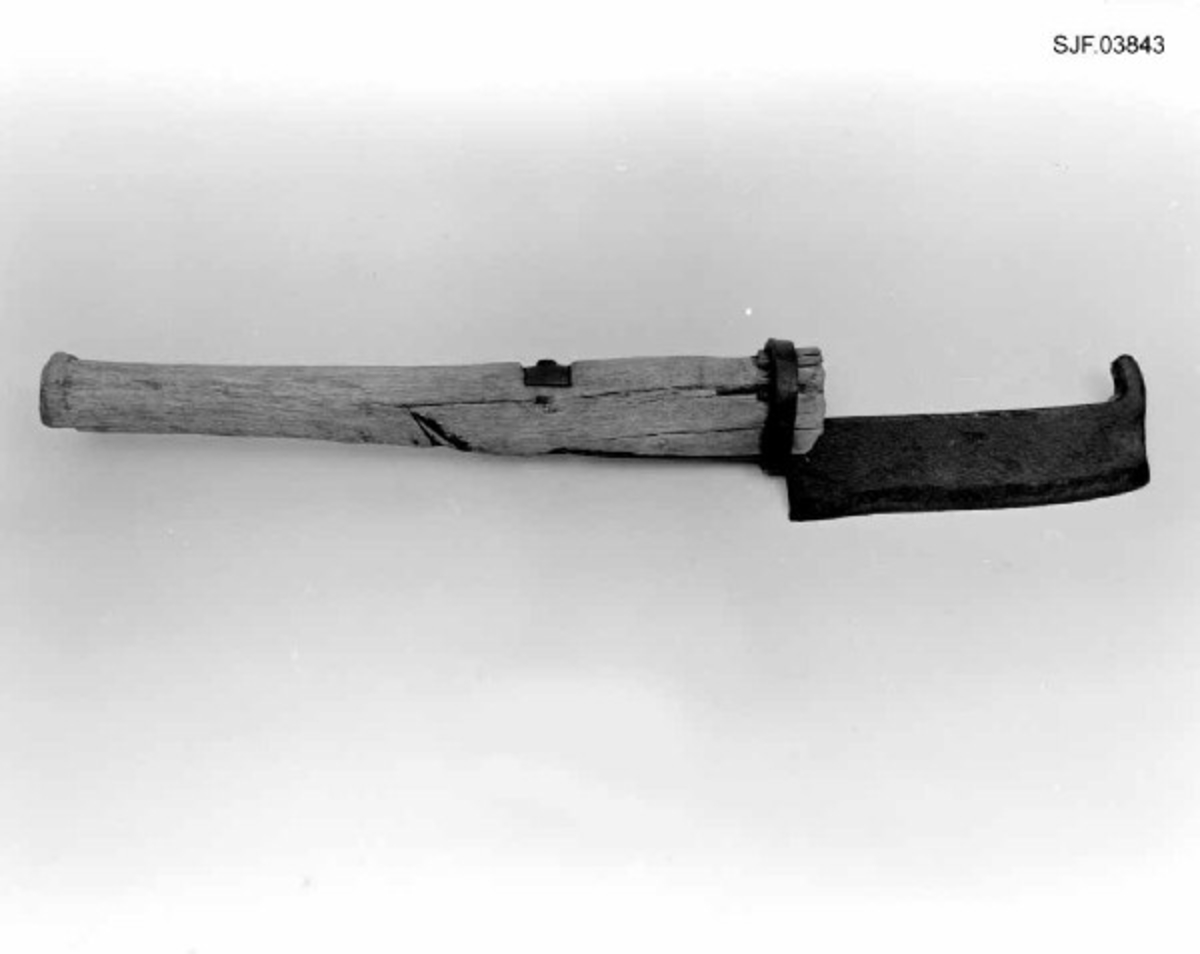 Lauvkniv, altså et redskap som ble brukt under innsamling av lauv som husdyrfôr. Redskapet er 47,5 centimeter langt. Knivbladet er 15,8 langt og 4,0-4,3 centimeter bredt. Bladryggen er 8-9 millimeter tjukk. Eggepartiet er fasslipt fra to sider. I den fremre enden av knivbladet er det smidd en oppovervendt krok (cirka 2 centimeter lang), antakelig for at brukeren av kniven skulle hekte denne over kvisten og trekke den ned i en rekkevidde der det var bekvemt å lauve. Skaftet er snaut 33 centimeter langt. Det er grovest i den fremre enden, men har også en markert endeknopp i den bakre enden. Tverrsnittet er ovalt. Skjeftinga er løst ved at en tange i enden av bladet er felt inn i et snaut 12 centimeter langt spor på den fremre delen av skaftbuken. Fra enden av dette sporet er den vinklete enden av tangen ført gjennom et hull i skaftet. Ytterenden er stuket mot ei jernskive på ryggsida av skaftet. Den fremre enden av tangen holdes i posisjon av en smidd jernring som omslutter både tangen og skaftenden. Veden i skaftet har sannsynligvcis krympet litt, noe som har gjort det nødvendig å sette inn en liten trekile mellom ringen og skaftet.