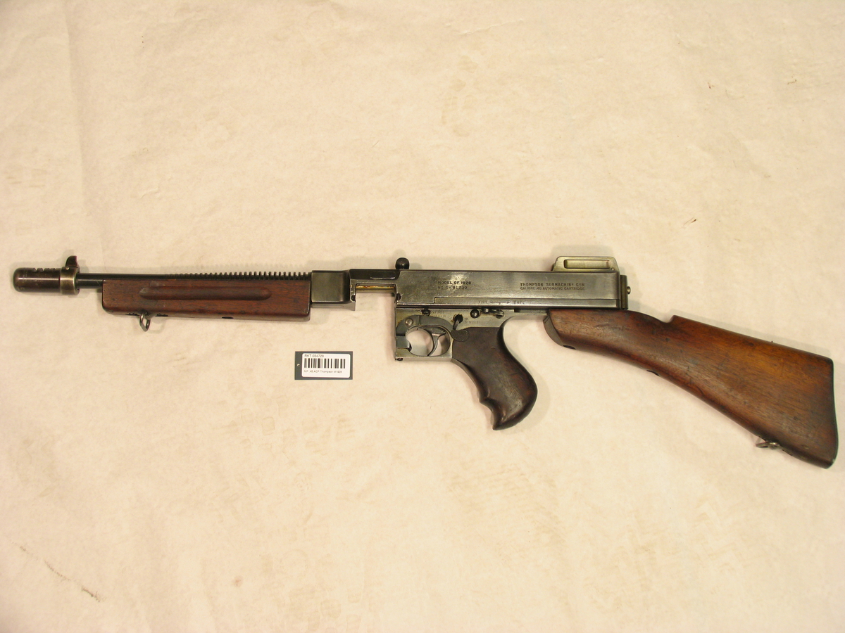 MED REM, OG EKSTRA PISTOLGREP FORAN. MERKING: THOMPSON SMG
CAL .45, AUTOMATIC CARTRIDGE, AUTO-ORDNANCE CORPORATION,
NEW YORK, N.Y. U.S.A., TRADE MARK THOMPSON REG US PAT. OFF P
FLAMMEDEMPER MERKET: CUTTS TRADE MARK (I ROMBE),
PAT. JULY 19 - 1927 NO. 1.636.357,
PAT. NOV   2 - 1928 N0. 1.615.383