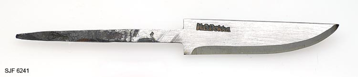 Knivblad, smidd av Hallvard O. Dokka (1921-1999) fra Notodden i Telemark. Denne gjenstanden er 15,3 centimeter lang. Sjølve bladet utgjør 7,3 centimeter av dette lengdemålet, resten er en tange, en jerntein som skal tappes inn i et knivskaft. Bladbredden er bortimot 1,7 centimeter, målt ved brystningen, altså på den aller innerste delen av bladet. Her er tjukkelsen 4,0 millimeter. Dette bladet har rettlinjet rygg. Smeden har plassert stempelet sitt - "H.O.Dokka" - bakerst på høyre bladside. Knivbladet er grovslipt på smergelskive med drøyt 4 millimeter brede slipefaser.