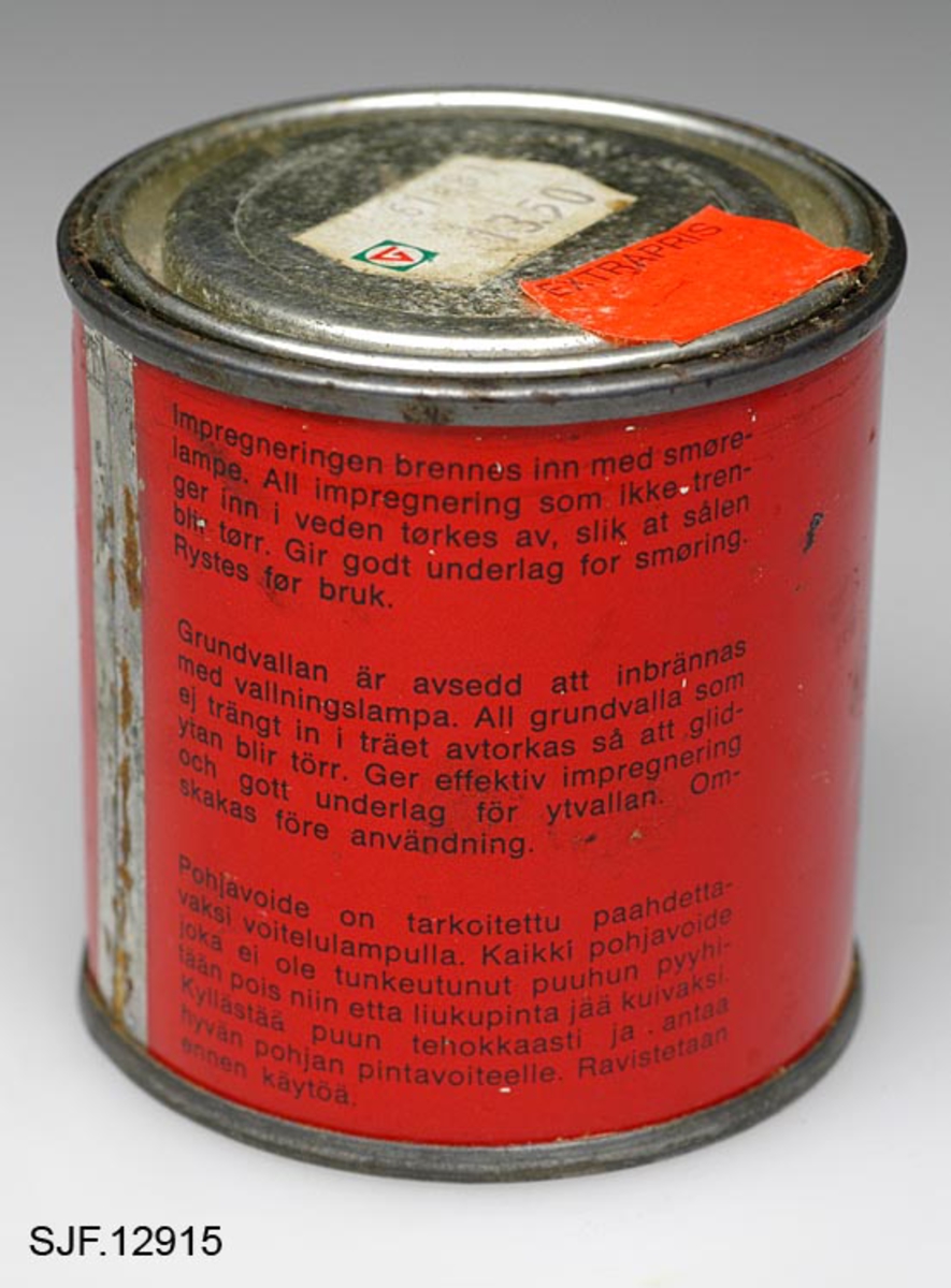 En boks, sylindrisk metallbeholder, med syntetisk impregnering for treski. Impregneringen holder vann og fuktighet borte fra skiene og gir bedre feste for smurningen som påføres etterpå. Denne impregneringen brennes inn i tresålen med smørelampe.  På metallbeholderens lokk er det påklistret to prislapper. Den ene står det "260111982 13. 50" på, den andre står det "extrapris" på. 
Det er noe innslag av rust der beholderen er skjøtet sammen. 