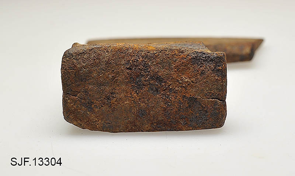 Økseblad uten skaft.  Redskapet er overført fra Borgarsyssel museum i Sarpsborg, dessverre uten proveniensinformasjon ut over at den skal være brukt i Østfold. 

Øksa er smidd, antakelig med innlagt stål i eggpartiet, men ettersom overflata er dekt av rust er det vanskelig å verifisere dette uten å foreta oppsliping.  Dette framstår som et forholdsvis tungt og bredt økseblad.  Med denne bladbredden har det neppe har vært beregnet på hogst, men det kan naturligvis ha vært brukt til barking, men også til ymse håndverksaktiviteter.  Den øvre delen (omkring øyet og nakken) er preget av slitasje.  Det nedenforliggende bladet er noe bredere.  Nakkedelen har opprinnelig vært flat og rektangulær, men den er brukt som hammer, noe som har ført til at godset er noe deformert og at det har dannet seg "skjegg" langs langsidene.  Øyet (skafthullet) har et dråpeformet tverrsnitt (cirka 5, 2 X 2, 6 centimeter). Godset mellom øyet og hammerflata på øksenakken er sprukket, noe som kan ha vært årsak til at redskapet ble kassert.  Eggdelen har betydelig større bredde enn nakkedelen. 