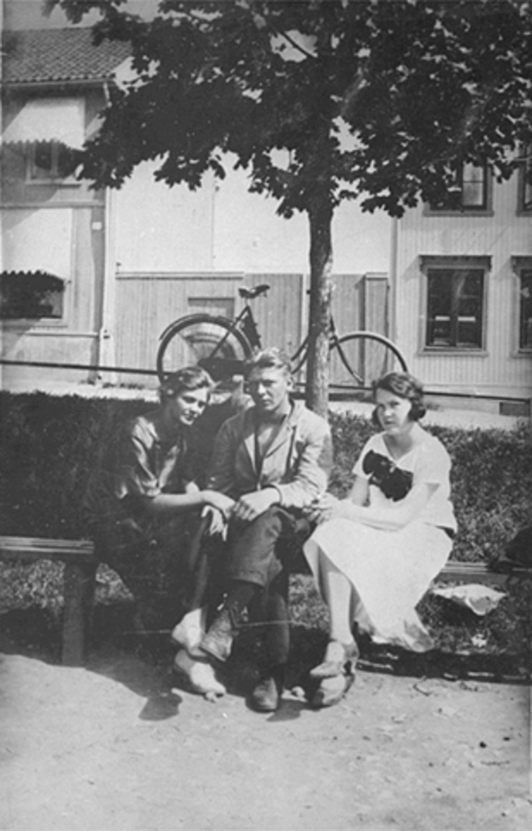 GRUPPE 3, 2 JENTER OG 1 GUTT PÅ BENK PÅ ØSTRE TORG, SYKKEL OG GRØNNEGATA I BAKGRUNNEN. 