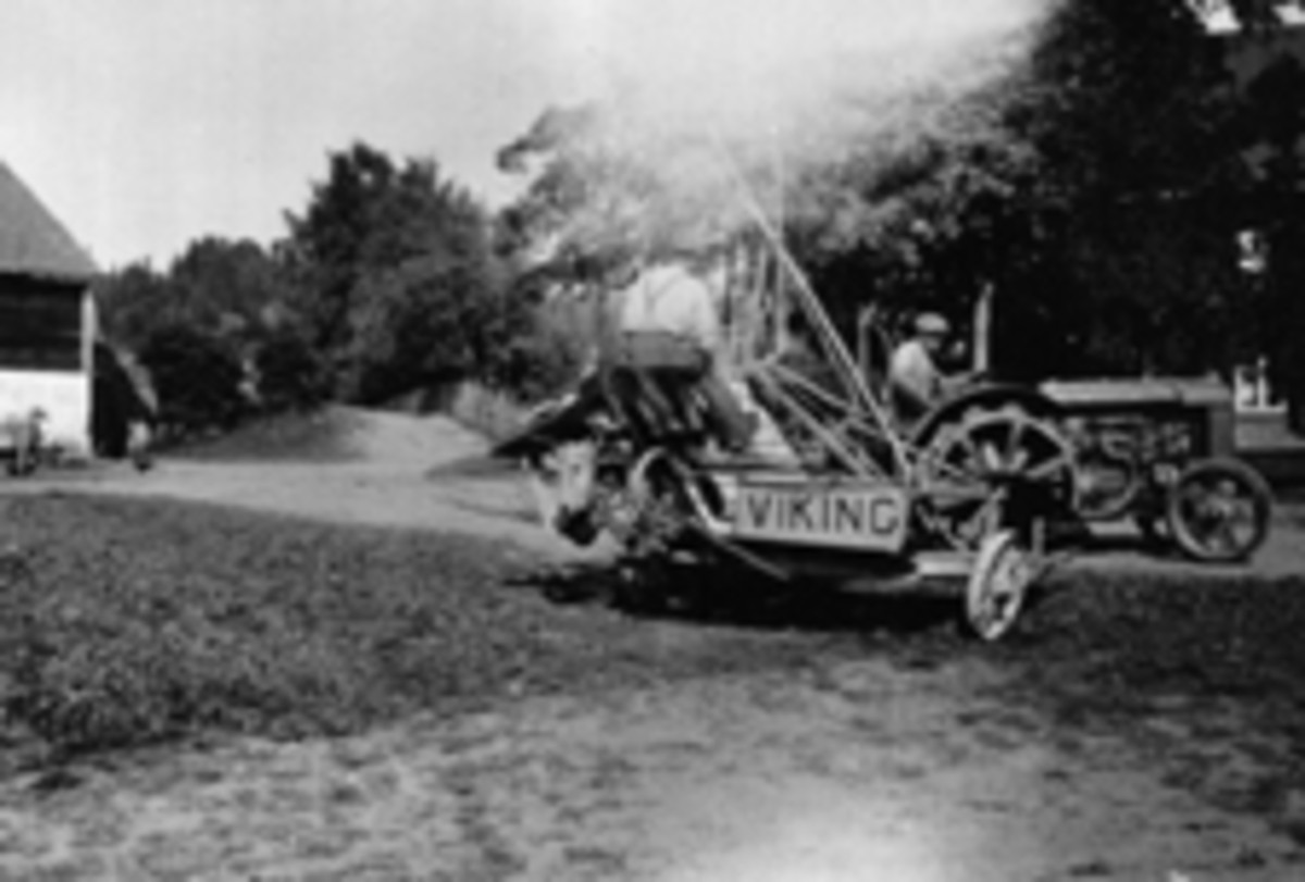Skuronn på Kirkejordet, Mellem Kise, Nes, Hedmark. Even Arnt Haugen (1909-1962) kjører traktor med Syverim Fagerheim på sjølbinderen "Viking".