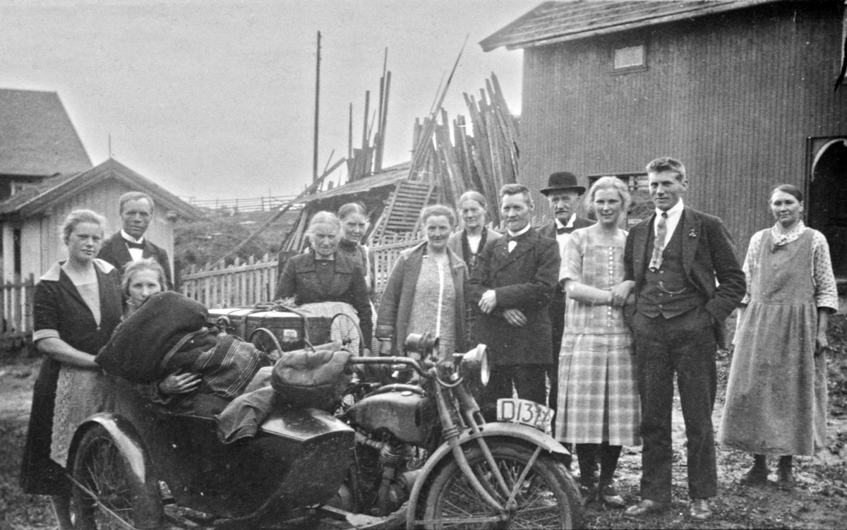 Motorsykkel ned sidevogn, Exelsior Super D-1311. Helen Hauger i sidevogna. Fra venstre er Gudrun Storlien, Ole Storlien, Marie Storlien. Bak er Helga Storlien, Inga Nordberg, Kristiane og Lars Storlien nummer 2 og 3 til høyre. Helt til høyre er Eline Martinsen. Jørgen Hauger eide sykkelen. Storlien, Veldre, Ringsaker.