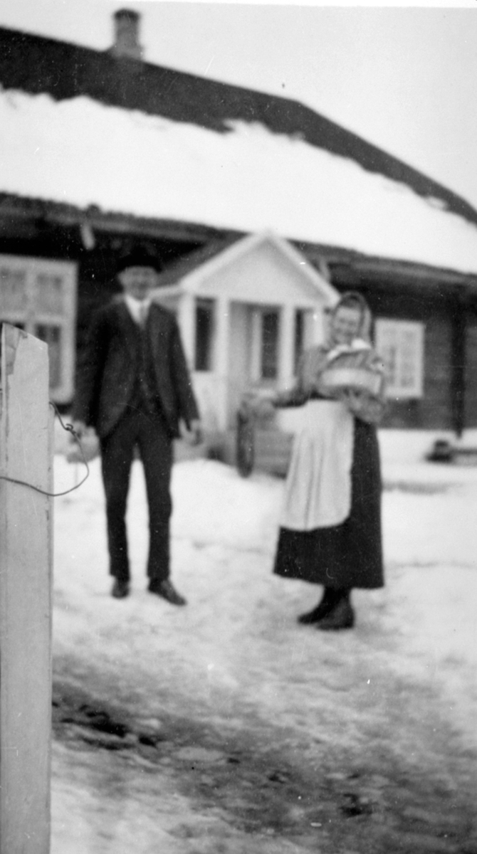 Hovedbygningen på Venningrud, Helgøya før den ble sydd. Vinter. Dame med ved og mann på tunet.