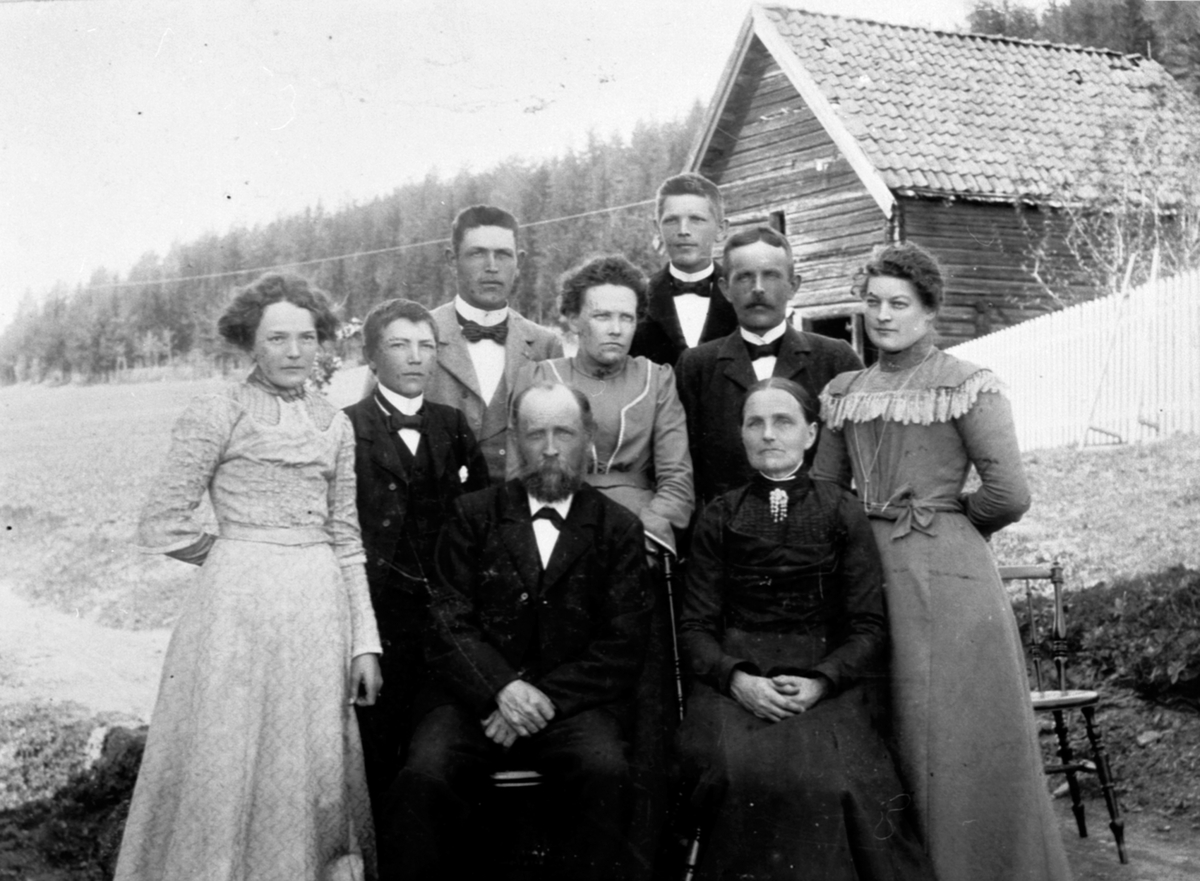 Familien på Røste, Helgøya. Sittende foran er Peder Olsen Røste (1850-1941) og Indiana Knutsdatter Røste (1849-1914). Stående fra venstre er Berte (1882-1985), Petter (1887-1964), Knut (1877-1952), Anna (1873-1966), Ole f.1876, Anna Godager (1882-1944).  Bak er Hans f.1879.