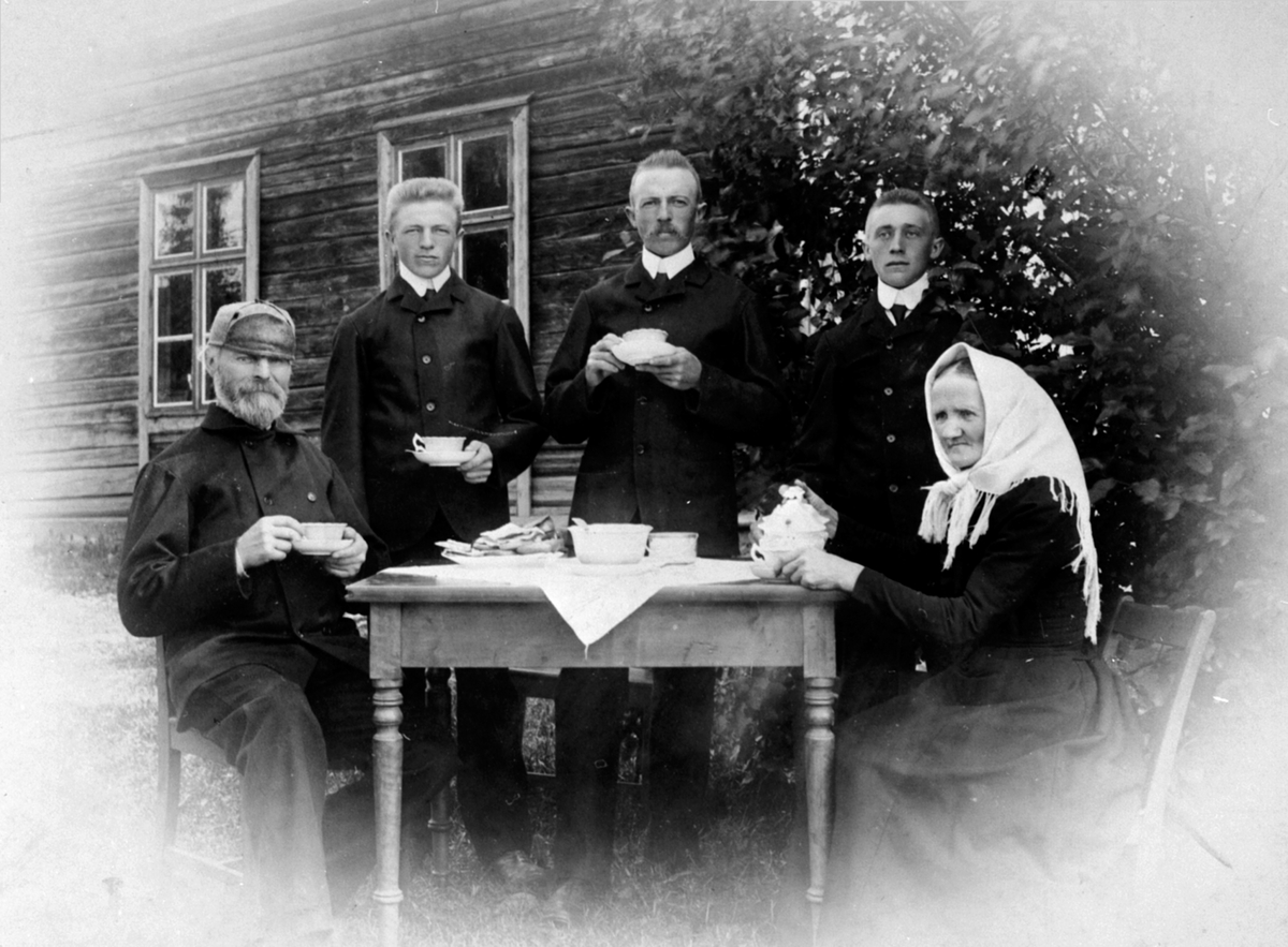 Familie på Svartshoel, Nes, Hedmark drikker kaffe i hagen. Fra venstre er Syver Mikkelsen Greften (1854-1933), Bernhard f.1888, Mathias f.1883, Hans f.1885, Agnete Halvorsdatter (1855-1926).