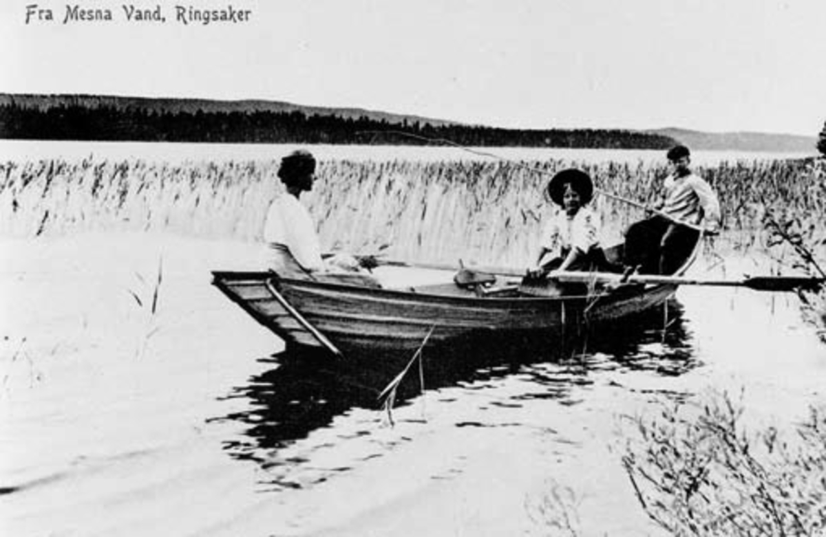 Folk med fiskestang  i robåt på Mesnavannet, Ringsaker. I båten er Astrid Wiik, Torgei Wiik med fiskestang og Hans Petter Jevanord.