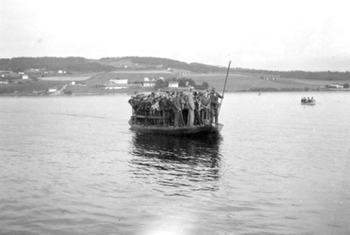 Ferje mellom Helgøya og Tingnes. Mjøsbåt bygd av Andreas Rønningen og satt i drift i 1928. Kapasitet på 2 personbiler. Her overlesset med gutter fra Toftes Gave. På 1930 tallet.