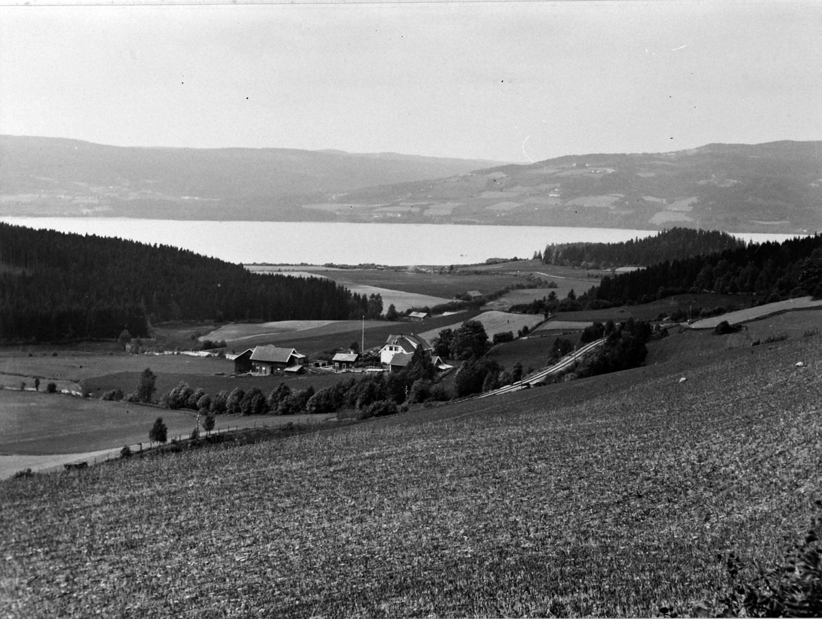 Ringsaker, Oversikt Bekkelund gård, jordbrukslandskap, Mjøsa i bakgrunnen, jernbanespor for Dovrebanen, 