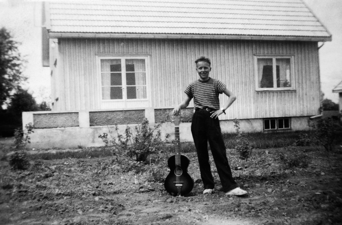 Terje Mølmen Moen med gitar utenfor Vonheim. Huset var et ferdighus tegnet av Hans Sørholtet av prefabrikerte lemmer fra Stange Bruk og ment for gjennoppbyggingen av Finmark etter krigen. Sju hus ble igjen i Stangebyen. Hanson gitaren ble kjøpt i Hamar Musikkforretning for penger tjent i gartneriet til Håkon Bø senior sommeren 1951. Bildet er tatt våren 1952. 
Se artikkel skrevet av Terje Mølmen Moen i "Gammalt frå Stange og Romedal 2010" utgitt av Stange historielag. 