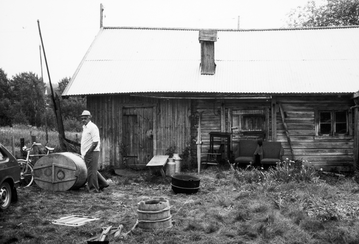 Auksjon ved Sæterskverna 12. juni 1980. Fjøset med diverse auksjonsgods utenfor. Personen er Ole Skåråsberget. 