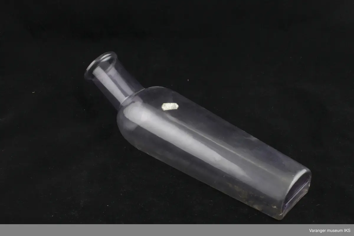 Urinflaske for sengeliggende i plast. Målestokk på flaskens underside.