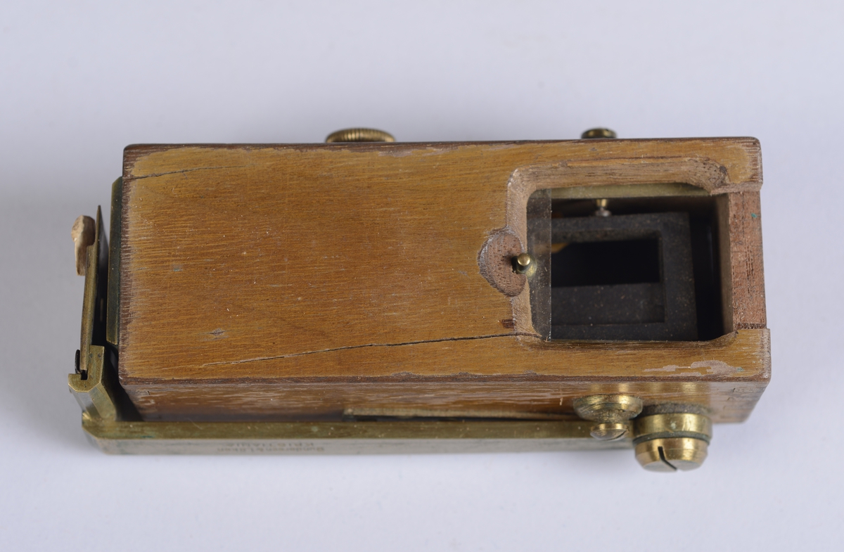 Måleinstrument oppbevart i rektangulært etui av skinn. Etuiet har reim og metallspenne for feste av lokket på front, og hemper på sidene.

Selve treesken:  10*3*4 cm.  Lengde på messingdelen:  10 cm.  Bredde på messingdelen:  1 cm.  Messingskiva fremme:  3*3 cm.  Etuiet:  6*10,5*4 cm.  Etui-lokket:  4,5*5,5*6,5 cm.
