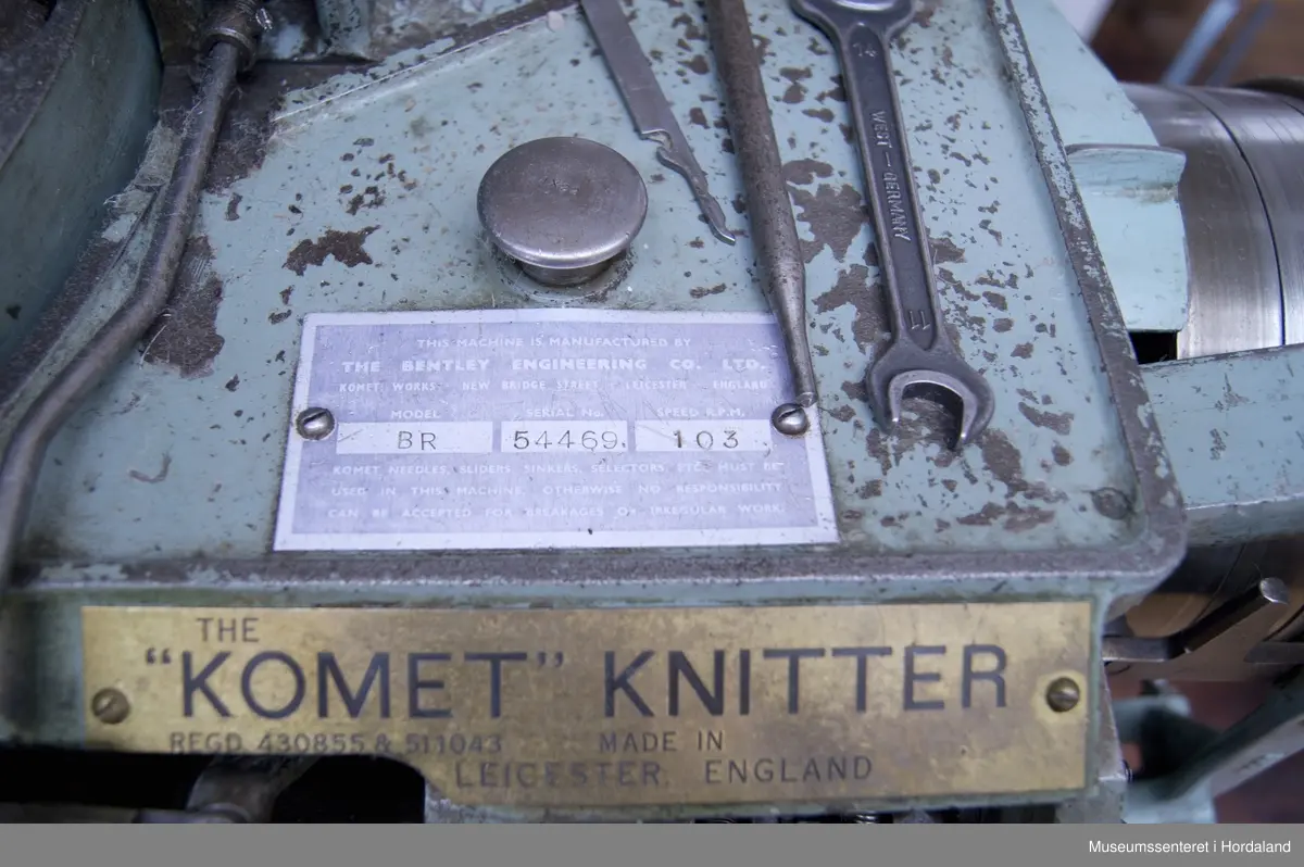 Mintgrøn Bentley sokkestrikkemaskin, "Komet Knitter" BR. Maskina strikkar raggsokkar og har forholdsvis stor sylinder.

Behaldaren nederst på høgre side til oppsamling av ferdig strikka sokkar er i metall: ein kan altså ikkje sjå når den er full. Men for erfarne strikkarar vart dette rutine - ein trong ikkje sjå det, ein visste når maskina var full.