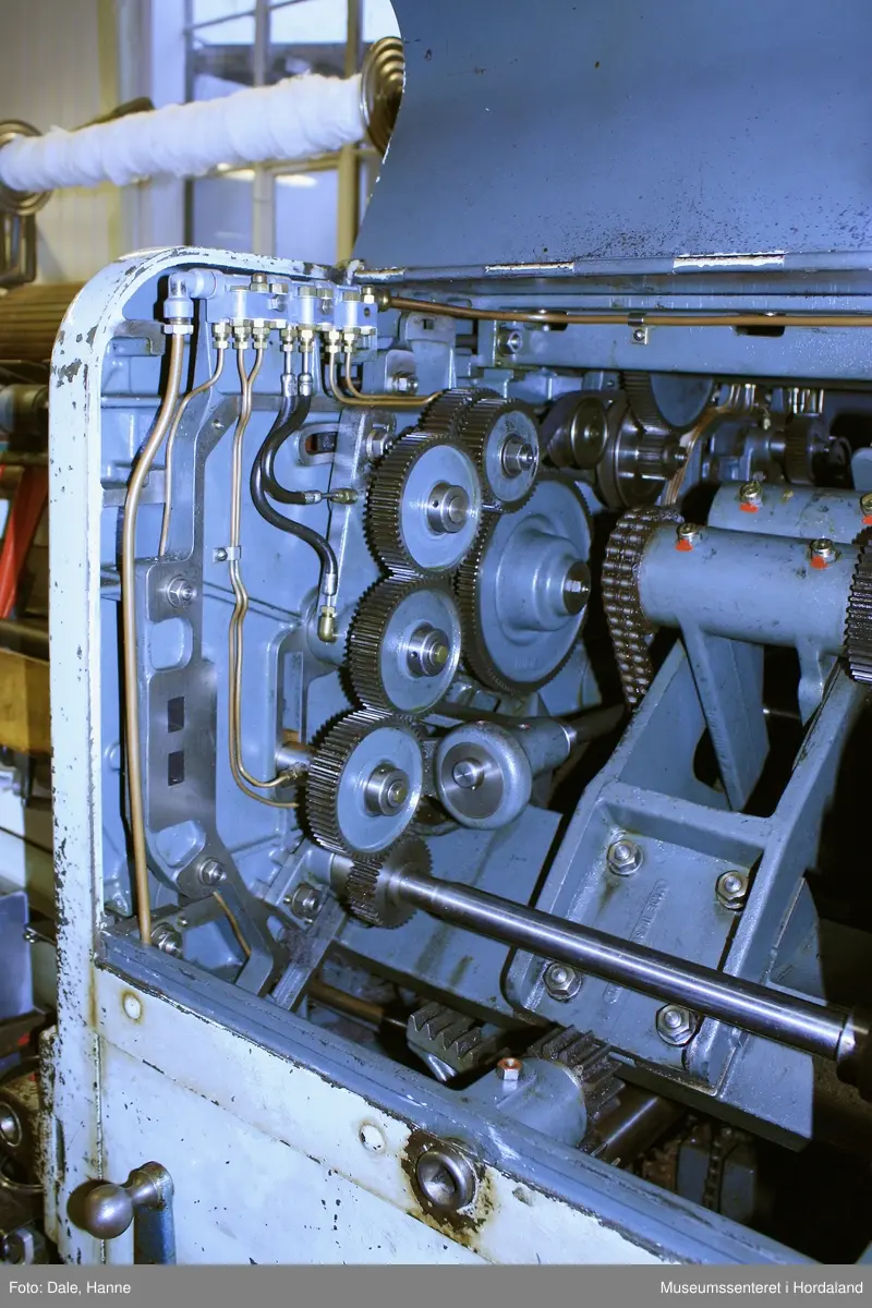 Elektrisk ringspinnemaskin (1958) frå det sveitsiske selskapet Rieter. Øvst på maskina plasserer ein spolane med forgarn frå kardemaskina. Reint teknisk er det tre hovudelement i spinninga:  forgarnet blir strukke, tvista (snodd) for å få meir styrke, før det ferdige garnet blir oppvikla på ein spole eller 'spinnepipe'. Tråden går under eit transporthjul i tre, gjennom støypte løpegangar og vidare nedover: Garnet blir snodd ved at garnet passerer ein løpar som beveger seg på ein ring, før det blir samla på ein sylindrisk metallspole. Det er ei rekkje små støvsugarar langs heile maskina, små røyr som stikk ut over spolane. Desse syg til seg støv og/eller tråden viss den ryk, for å unngå at den kjem inn i maskina. Trådrestar og støv blir samla opp i eit oppsamlingskammer på venstre sida av maskina. Der er det òg ein målar som måler kor mykje maskina spinner.

Drivverket og ein stjernemotor sit på høgre sida av maskina. På sida står det "Rieter" i raudt, og det er to målarar som måler omdreiingar/hastigheit på maskina. Det er ei rekkje med 136 koner på kvar side. Maskina kan byggjast på i seksjonar, og slik utvidast etter behov, noko som er vanleg for spinne- og spolemaskiner.