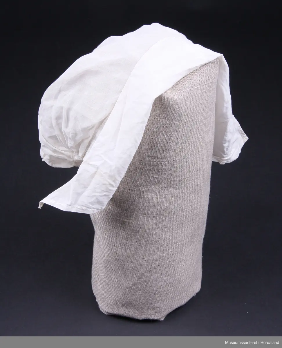 Svært tynt bomullslerret og brem i litt tjukkare lerret ( men framleis tynt - batist).
Strikk bak i nakken. Sølve hua er i eit stykke, medan bremmen har saum midt oppe på hovudet.Smal maskinsydd fall på bremmen.