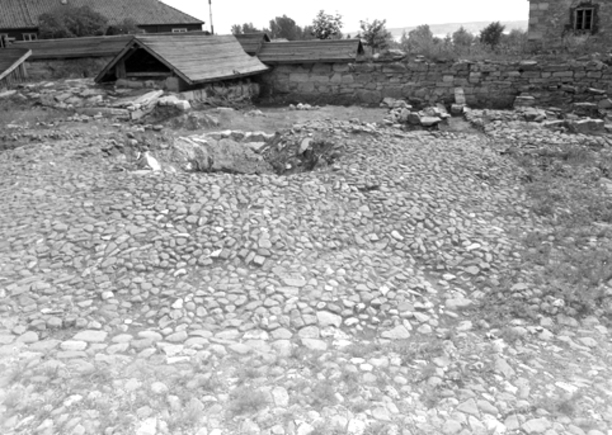 Arkeologiske undersøkelser i Hamar bispegård, Domkirkeodden, Hamar 1956. Brolegging i bispegårdens midtparti og rester av brønnen.