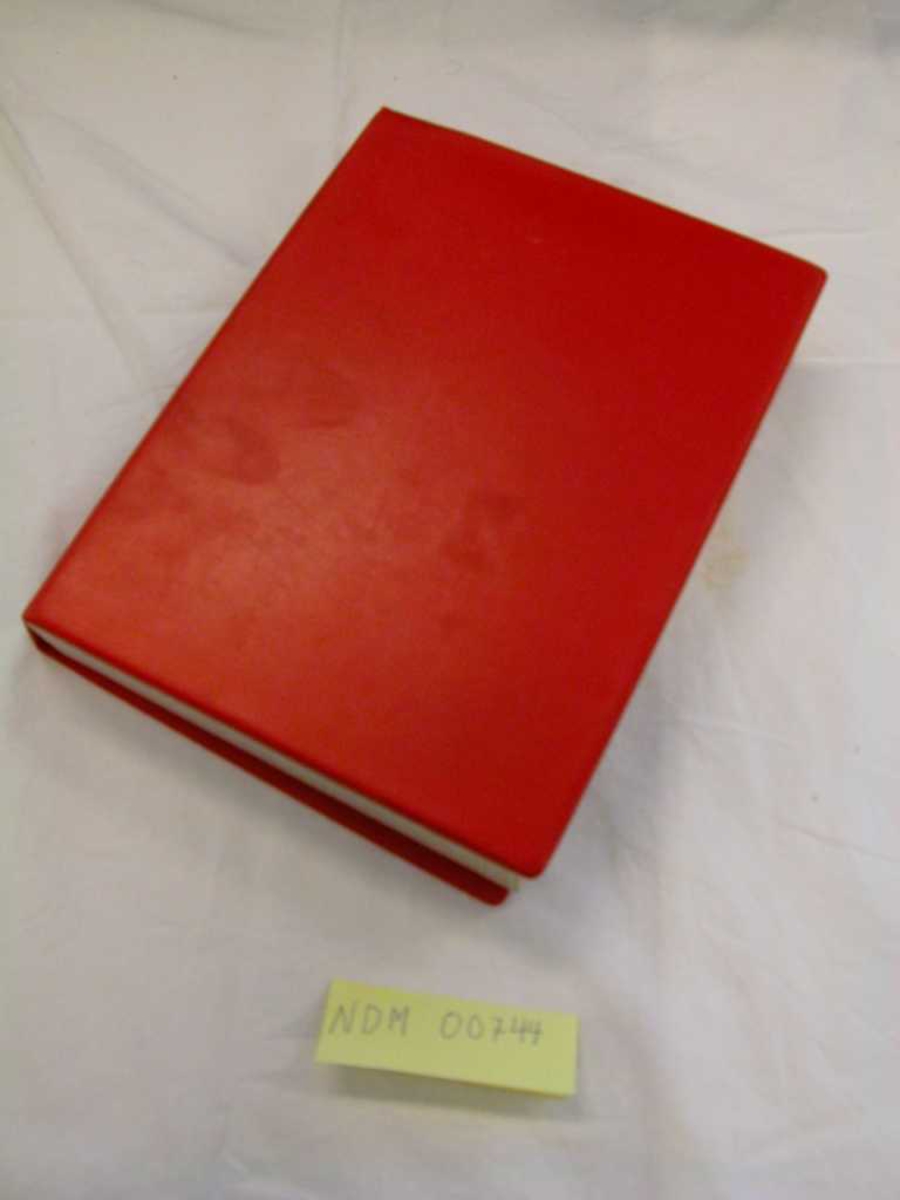 Rød NKS-perm med skolearbeid.