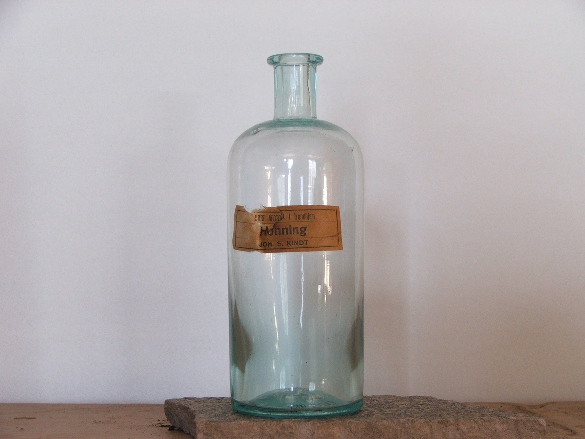 En rund, klar flaske med etikett.