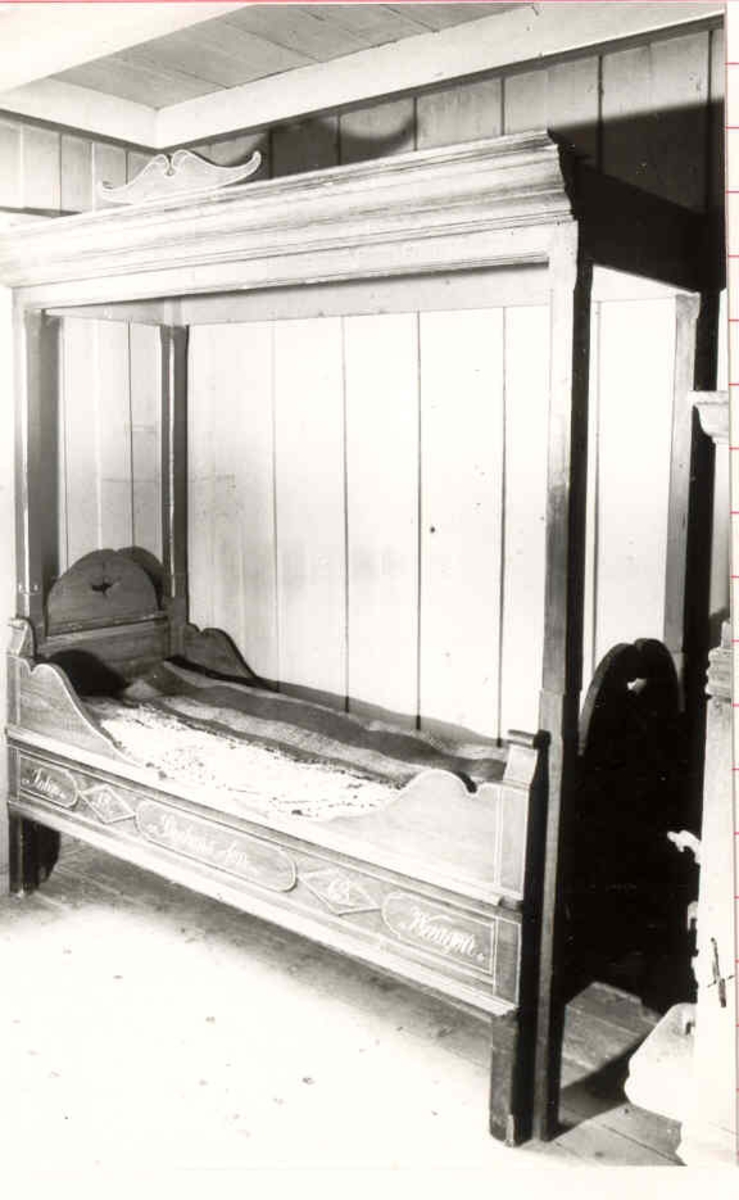 En skuvseng med 4 sengestolper og himling, utskjæringer ved sengevangene og øverst. Mangler forheng. Inskripsjon malt i gult foran. Himlingen er festa med tapper på sengestolpene.