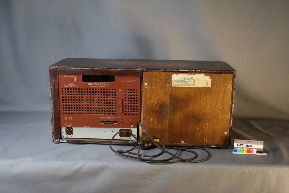 Brun rektangulær radio. Forside: skala med fire funksjons- og søkeknapper. Indikator for signalstyrken på stasjonen, kalt "trolløye". (Jo sterkere stasjonen er, desto større blir "øyet". Dette skjer ved hjelp av et elektronisk fluoriserende belegg.) Høyttaler med trekk av tekstil. Bakside: intakt bakplate med uttak for antenne, grammofon, jord, strøm, ekstrahøyttaler, styrkekontroll og apparathøyttaler.