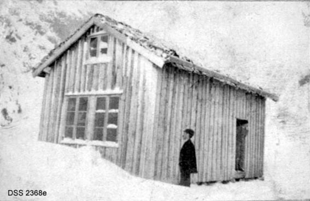 Haukeliseter fjellstue.  Seks vinteropptak, antakelig fra tida like før 1900.  A. Våningshus i djupsnø, en panelt og kvitmalt bygning til høgre, en uthusbygning og et våningshus i drakestil til venstre for dette.  B.  Uthus og våningshus i drakestil, mann med hund foran drakestilhuset.  C.  Våningshus med drakestilpreg, der særlig en toetasjes fløy til høyre i bildet har lånt trekk fra stabbur og loft i Telemark og Numedal.  D. Panelt og kvitmalt våningshus i en etasje, men med rom på loftet.  Snøen står om lag midt på veggen på forsida av huset, nestet opp til raftet på baksida.  En mann bærer noe mot inngangen.  E.  Bryggerhusliknende bygning med torvtak.  En mann ved langveggen og en i døra.  F.  11 personer foran inngangen til den kvite bygningen på fjellstua. Reinsdyrgevir over døra. 