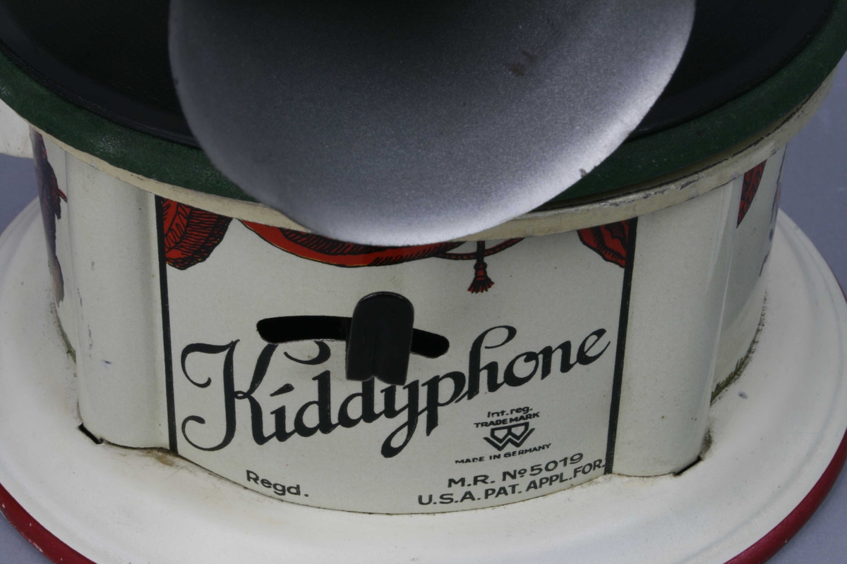 Leketøysgrammofon for avspilling av plater. Fjærmekanikk innvendig som trekkes opp for avspilling.
Nål og trakt som høytaler. 
Alle deler er i metall. Topplaten er malt grønn og limt rett på metall. Muligens en slags vinylmaling.