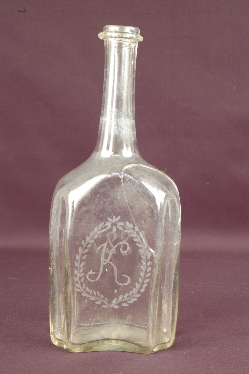 Åttekantet brennevinsflaske med lang tut. Gravert tekst på blankt glass.