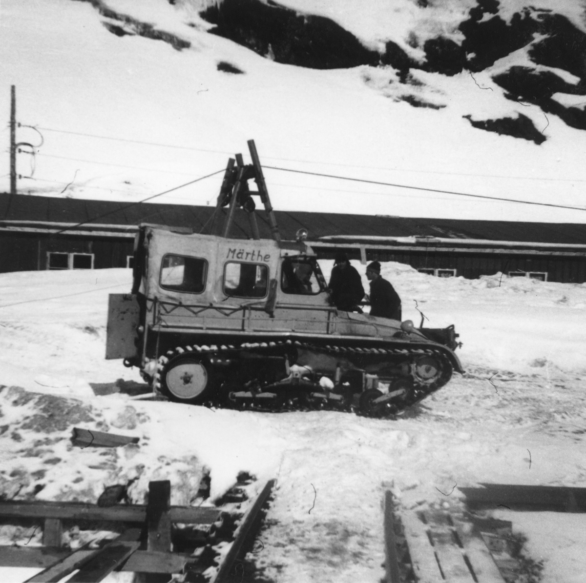 Anleggsarbeidarar med ein Märthe beltebil, weasel, ved brakkene i Tyssedalsfjellet