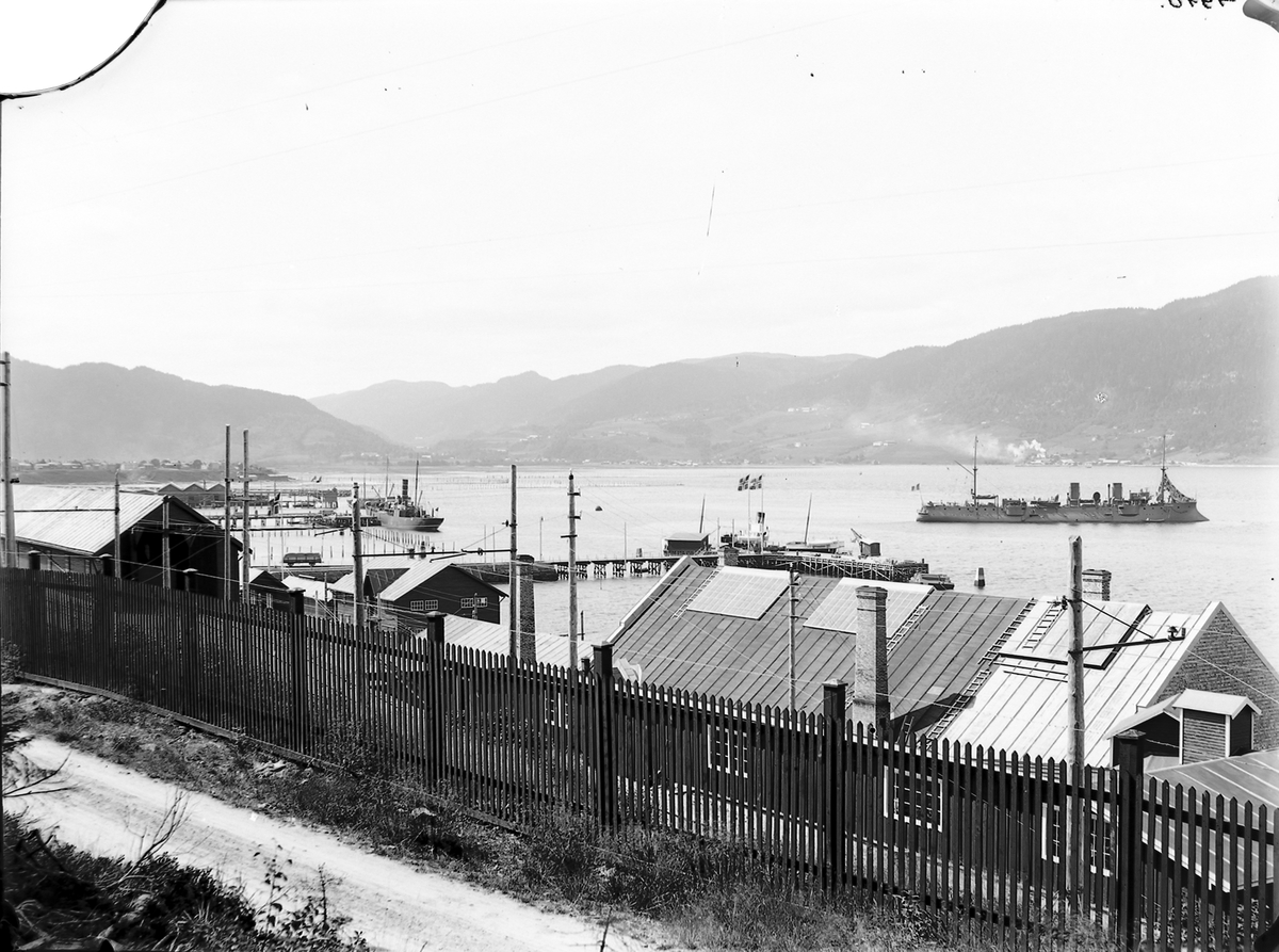 Thamshavn. Stakittgjerde i forgrunnen. Krysseren "Lavoisier" på fjorden.